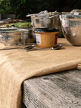 Bowls containing food for a picnic laid out on a wooden table.